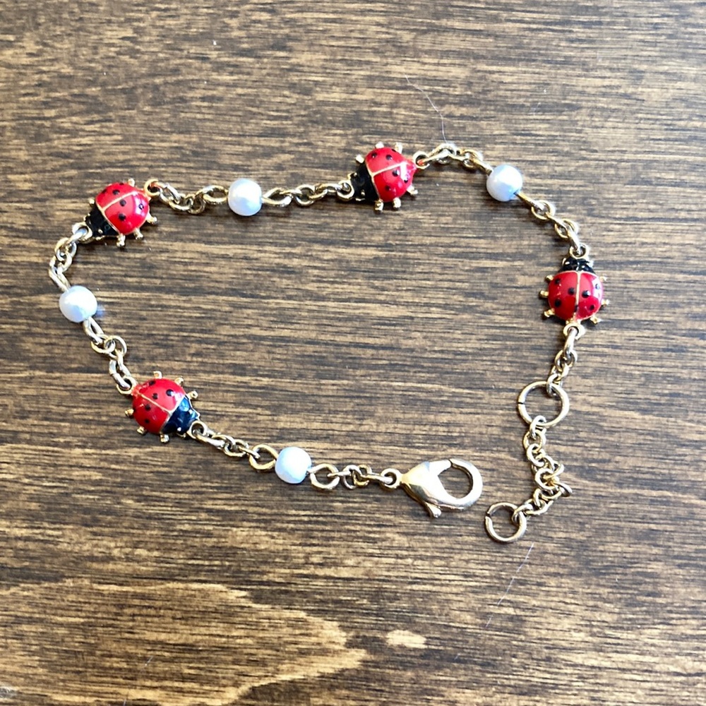 Gold tone ladybug bracelet with faux pearls